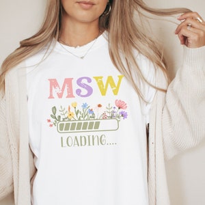 May include: White t-shirt with a graphic of a progress bar that says "MSW Loading..." with colorful flowers above the bar.