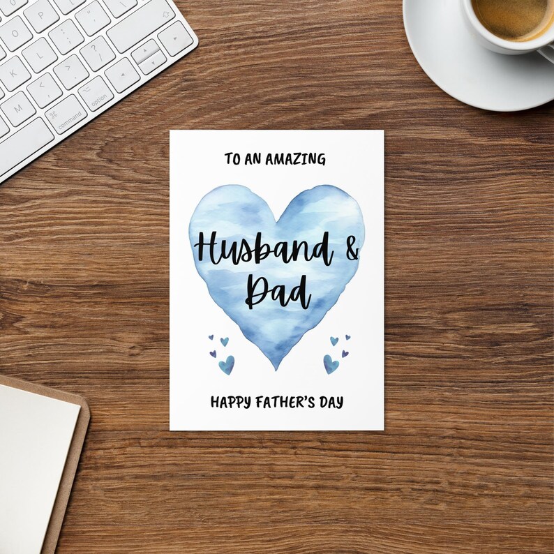 Puede incluir: Una tarjeta blanca con un coraz&oacute;n azul de acuarela que dice "To an amazing Husband & Dad" y "Happy Father's Day".