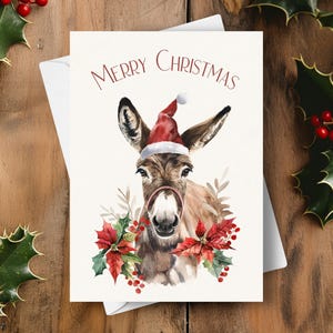Tarjeta navideña con burro, gorro de Papá Noel y guirnalda de flores de Pascua rojas, adorable y lindo regalo navideño con forma de burro, ilustración de arte en acuarela