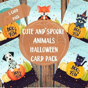 Op de afbeelding: Een set van vijf Halloween-kaarten met schattige dierenillustraties. Elke kaart toont een ander dier, zoals een vos, een wasbeer, een dalmatiër en een zwarte kat, allemaal op pompoenen. De kaarten hebben een lichtblauwe achtergrond met spinnenwebben en de tekst "Boo to You."