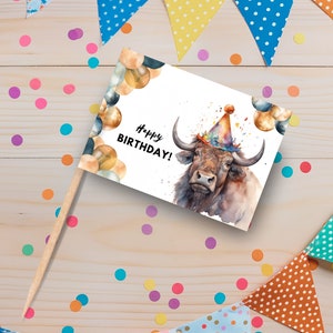 May include: A white card with a watercolor illustration of a brown bull wearing a party hat. The bull is surrounded by gold and blue balloons. The card says "Happy Birthday!" in black text.