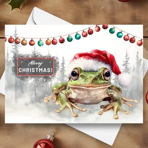 Frosch-Weihnachtskarte, frohe Weihnachten-Frosch, der einen Weihnachtsmannhut in einer schneebedeckten winterlichen Szene, netter grüner Frosch-Feiertagsgeschenk-Aquarell-Illustration trägt