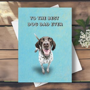 Puede incluir: Tarjeta de felicitación con un perro Braco Alemán sobre un fondo azul claro. El texto "TO THE BEST DOG DAD EVER" está escrito en negro. El perro tiene manchas marrones y blancas y mira hacia arriba.