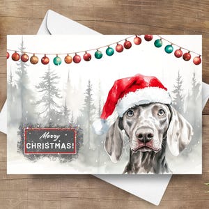 Tarjeta navideña de Weimaraner, perro feliz de Navidad con gorro de Papá Noel en una escena invernal nevada, ilustración de acuarela de regalo navideño de perro gris