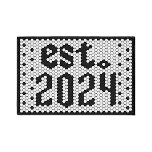 May include: Black and white doormat with a honeycomb pattern and the text "Est. 2021" in a stylized font.