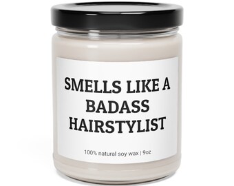 May include: A white candle jar with a black lid. The label reads "Smells Like A Badass Hairstylist" and "100% natural soy wax | 9oz".