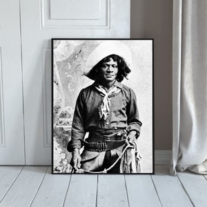 Puede incluir: Fotografía en blanco y negro de un hombre con un sombrero de vaquero y un pañuelo. Sostiene una cuerda en su mano derecha y una pistola en su mano izquierda. La foto está enmarcada en un marco negro.