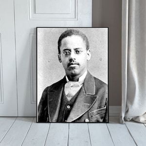 May include: Black and white portrait photograph of a man wearing a suit, tie, and glasses. He is looking directly at the camera.