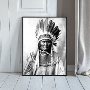 Puede incluir: Retrato en blanco y negro de un hombre nativo americano con un tocado tradicional con plumas. Está mirando directamente a la cámara con una expresión seria.