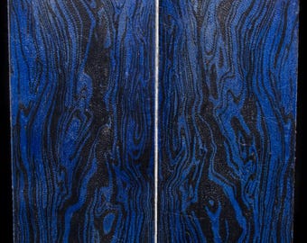 May include: Two rectangular pieces of wood with a striking blue and black wood grain pattern. The grain has a flowing, organic appearance, with the blue sections creating a vibrant contrast against the black.