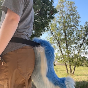 Puede incluir: Una cola esponjosa azul y blanca con una punta blanca, unida a un cintur&oacute;n negro que se lleva alrededor de la cintura.