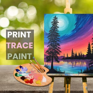K&ouml;nnte beinhalten: Eine Holzpalette mit einer Vielzahl von bunten Farben, Pinseln und einem Leinwandbild eines farbenfrohen Sonnenuntergangs mit einer Silhouette von B&auml;umen und einem See. Die Leinwand steht auf einem Staffelei. Der Text "PRINT TRACE PAINT" ist im Bild sichtbar.