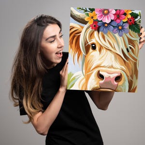 May include: A painting of a Highland cow wearing a flower crown. The cow has a light brown coat and a pink nose. The flowers in the crown are pink, purple, yellow, and orange.