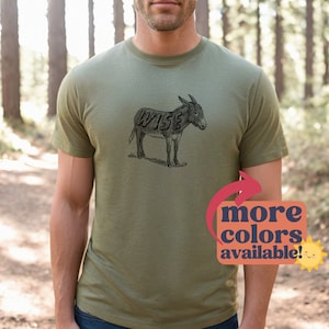May include: A green t-shirt with a black and white illustration of a donkey with the word "WISE" spelled out on its body. The text "more colors available!" is in a red and orange box with a sun graphic.