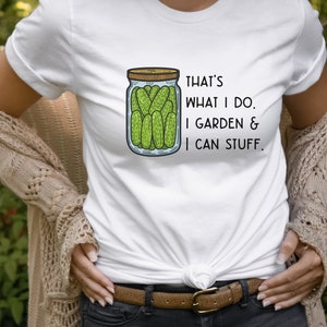 May include: White t-shirt with a drawing of a jar of pickles and the text "That's what I do. I garden & I can stuff."