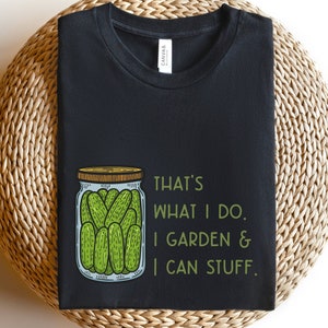 May include: Black t-shirt with a green and white illustration of a jar of pickles. The text "That's what I do. I garden & I can stuff." is printed on the shirt.