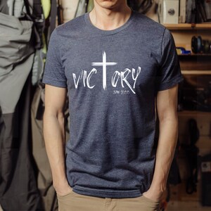 May include: A navy blue t-shirt with a white cross and the word "VICTORY" written in white with a white "John 3:16" underneath.