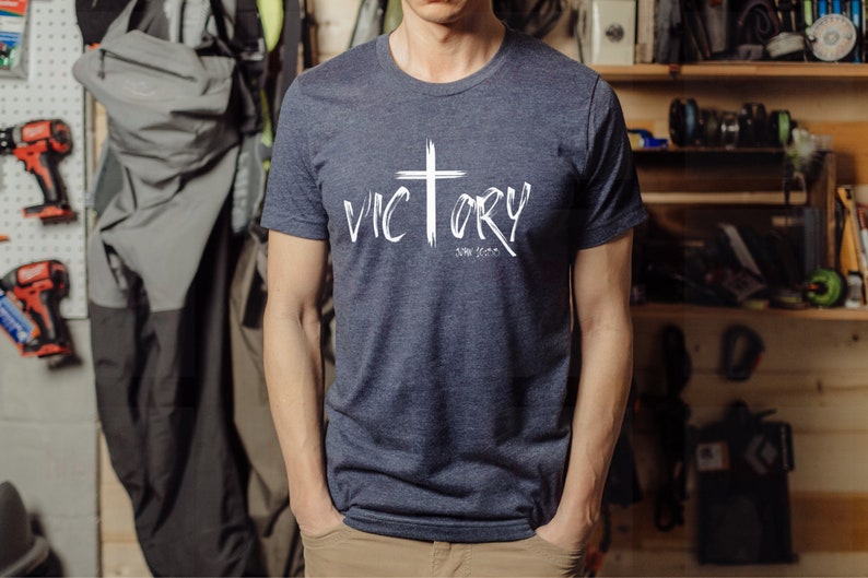 May include: A navy blue t-shirt with a white cross and the word "VICTORY" written in white with a white "John 3:16" underneath.