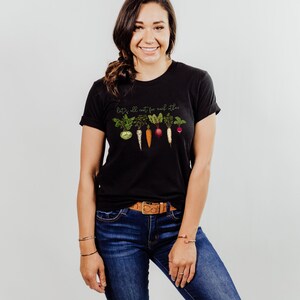 May include: Black t-shirt with a graphic of vegetables and the text "Let's all root for each other".