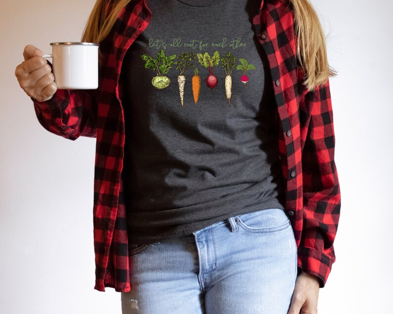 May include: A dark gray t-shirt with a graphic of vegetables and the text "Let's all root for each other".