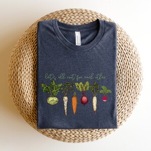 May include: A dark heather grey t-shirt with a graphic of various vegetables and the text "let's all root for each other".