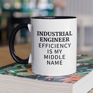 May include: White ceramic mug with a black handle and black rim. The mug has black text that reads "INDUSTRIAL ENGINEER EFFICIENCY IS MY MIDDLE NAME".