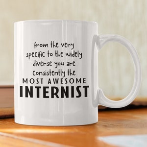 May include: White ceramic coffee mug with a black inscription that reads "from the very specific to the widely diverse you are consistently the MOST AWESOME INTERNIST".