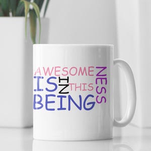 May include: White ceramic mug with the text "AWESOMENESS IS IN THIS BEING" in purple, pink, and blue lettering.