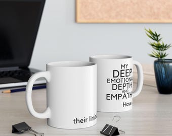 May include: Two white ceramic mugs with black text. One mug reads "My Deep Emotional Depth and Empathy Have" and the other reads "their limits". The mugs are on a light-colored surface.