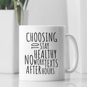 Peut inclure: Une tasse en céramique blanche avec du texte noir qui dit "Choisir de rester en bonne santé, pas de textos de travail après les heures de travail".