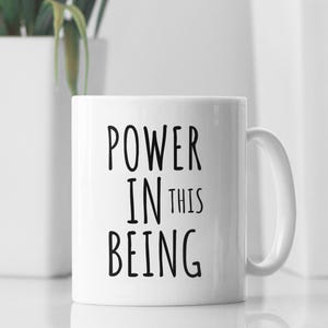 May include: White ceramic mug with black text that reads "POWER IN THIS BEING".
