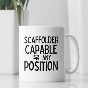 May include: White ceramic mug with black text that reads "Scaffolder Capable of Any Position".