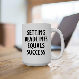 Op de afbeelding: Een witte keramische koffiemok met zwarte tekst die "Setting Deadlines Equals Success" luidt.