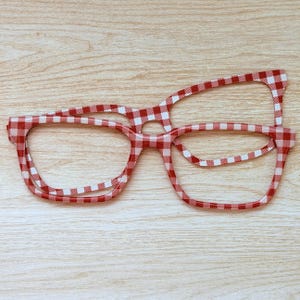 May include: Red and white gingham pattern eyeglasses frames. The frames are made of a lightweight material and have a classic rectangular shape. The glasses are a fun and stylish accessory.