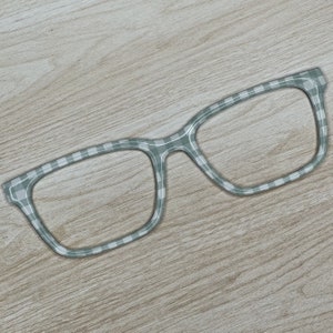 May include: A pair of eyeglasses with a checkered pattern on the frame. The frame is a light gray color.
