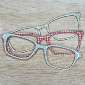 May include: Three pairs of eyeglasses with different colored frames. The frames are patterned with a checkered design in red, blue, and green.
