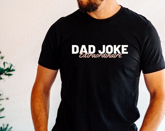 May include: A black t-shirt with the text "DAD JOKE Extraordinaire" in white and pink lettering.