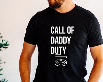 May include: Black t-shirt with white text that reads "Call of Daddy Duty" and a white video game controller graphic.