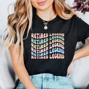 May include: A black t-shirt with the text "Retired Legend" repeated in a rainbow of colors. The text is in a retro font style.