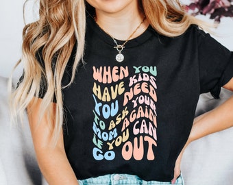 May include: A black t-shirt with a colorful graphic that reads "When you have kids you need to ask your mom again if you can go out".