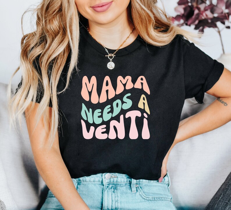 May include: A black t-shirt with the text "Mama Needs a Venti" in colorful, retro-style lettering.