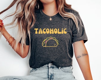 May include: A dark gray t-shirt with the text "TACOHOLIC" in yellow letters and a cartoon taco graphic.