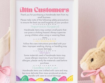 May include: A white framed sign with pink, yellow, and blue text that reads "Attn Customers". The sign provides instructions for handling handmade items, including supervision required, care instructions, allergies, and handling with care. The sign is in front of a pink background with two plush bunny rabbits.
