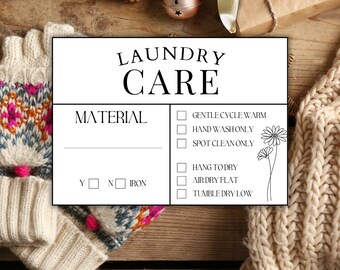 May include: A white laundry care instruction card with the words "LAUNDRY CARE" in a decorative font. The card includes checkboxes for washing instructions and a section for material type. The background is a wooden surface.
