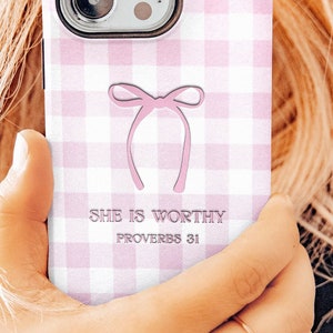 May include: A pink and white gingham phone case with a pink bow and the text "She is worthy Proverbs 31"