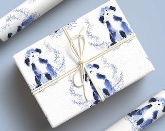May include: White gift wrap with a blue watercolor illustration of a dog inside a wreath. The wrapped gift is tied with twine. Two rolls of matching wrapping paper are also visible.