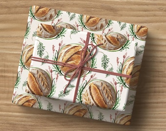 May include: Two gift-wrapped packages with a repeating pattern of watercolor bread loaves and greenery on a cream background. The packages are tied with a brown ribbon, creating a rustic and charming aesthetic.