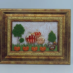 May include: A framed autumn-themed artwork featuring a gold-colored frame. The artwork depicts a scene with pumpkins, trees, and a squirrel. The pumpkins are orange and red with jeweled accents. The trees are green, and the squirrel is brown and jeweled.