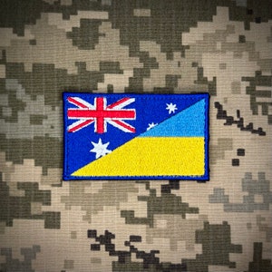 May include: A blue and yellow patch with the Australian flag and the Ukrainian flag on a camouflage background.
