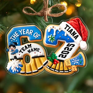 May include: A personalized Christmas ornament shaped like the number 52, with a cheerleader design. The ornament includes the text "The Year of", "Team Name", "Tiana", and "2025". It features a red Santa hat and blue and gold accents.
